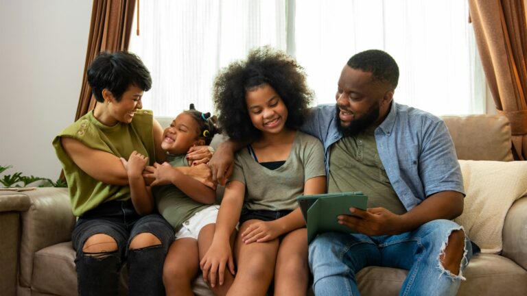 A family laughing together on the living-room sofa