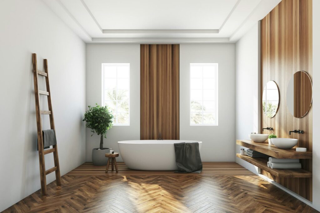 A bright bathroom with a freestanding tub between two tall windows
