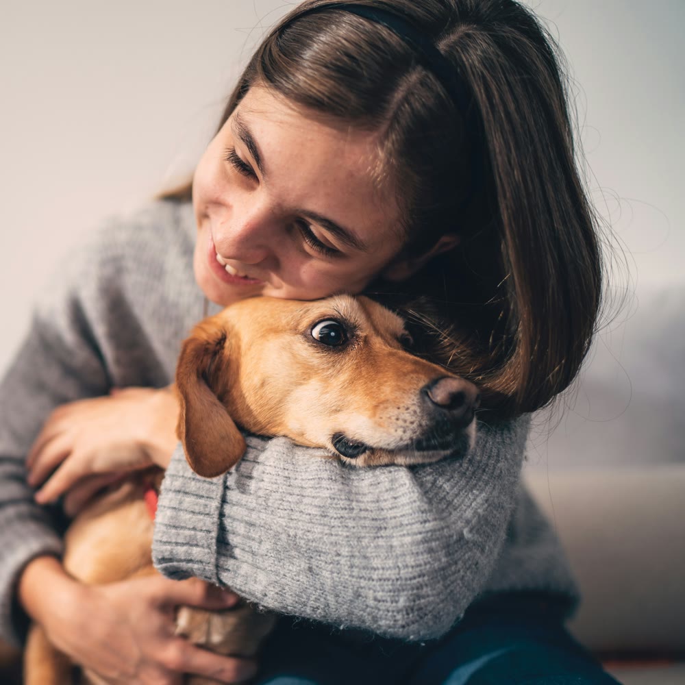 A smiling girl hugging her dog close